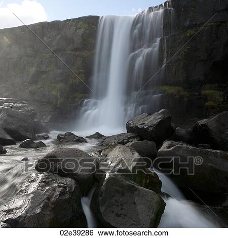 Stock Photograph - Waterfall cascading over cliff onto boulders. Fotosearch
