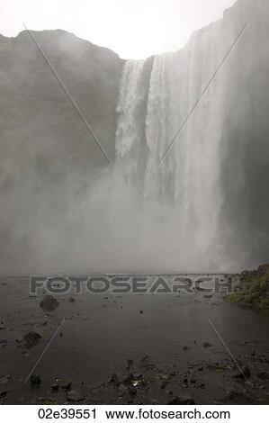 Stock Image - Waterfall over a cliff in Iceland. Fotosearch