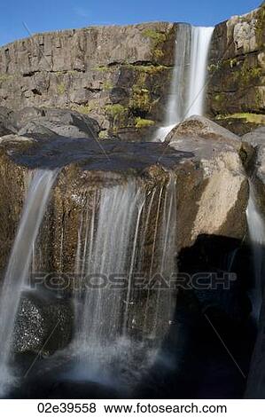 Waterfall over rocky cliffs in Iceland View Large Photo Image Stock Photo - Waterfall over rocky cliffs in Iceland. Fotosearch