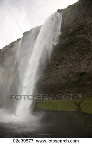 Waterfall over rocky cliffs in Iceland View Large Photo Image Stock Photo - Waterfall over rocky cliffs in Iceland. Fotosearch