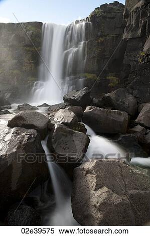 Waterfall over rocky cliffs in Iceland View Large Photo Image Stock Photography - Waterfall over rocky cliffs in Iceland. Fotosearch