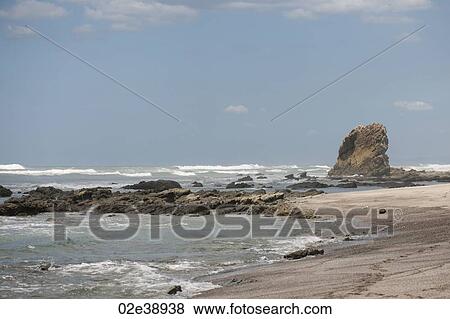 Waves lapping up against a sandy beach with an outcropping of rocks, and a stack in the background View Large Photo Image Stock Photo - Waves lapping up against a sandy beach with an outcropping of rocks, and a stack in the background. Fotosearch