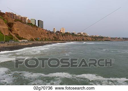 Stock Photograph - Waves with a city in the background, Miraflores District, Lima Province, Peru. Fotosearch