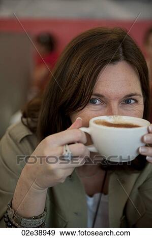 Woman peeking over a full cup of milky coffee View Large Photo Image Stock Photo - Woman peeking over a full cup of milky coffee. Fotosearch