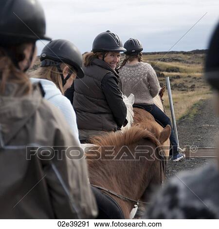 Stock Image - Woman smiling while riding Icelandic horses in a row. Fotosearch