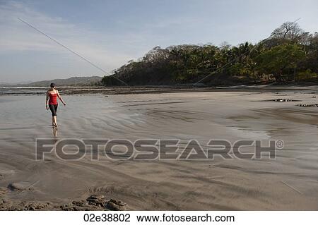 Stock Image - Woman walking on the beach, San Jose Costa Rica. Fotosearch