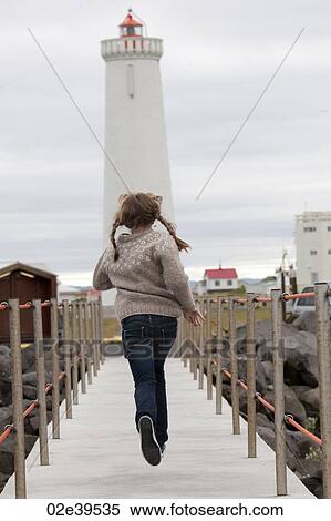 Stock Photography - Young girl in pigtails running over a walkway in Iceland. Fotosearch