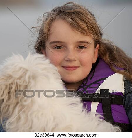 Young girl wearing a life jacket with her dog in Lake of the Woods, Ontario View Large Photo Image Picture - Young girl wearing a life jacket with her dog in Lake of the Woods, Ontario. Fotosearch