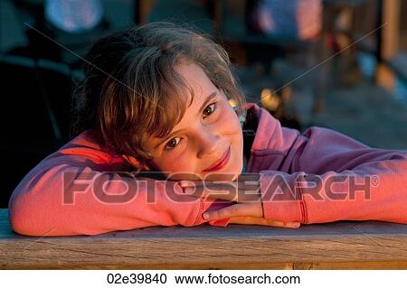 Young girl with her head on her arms looking at the camera View Large Photo Image Stock Image - Young girl with her head on her arms looking at the camera. Fotosearch