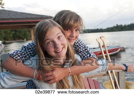 Younger girl embracing her older sister at Lake of the Woods, Ontario View Large Photo Image Stock Photo - Younger girl embracing her older sister at Lake of the Woods, Ontario. Fotosearch