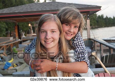 Stock Photograph - Younger girl embracing her older sister at Lake of the Woods, Ontario. Fotosearch