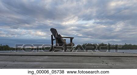 Stock Photo - Adirondack chair on dock at lake, Lake Of The Woods, Ontario, Canada. Fotosearch