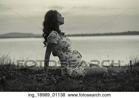 Stock Photo - Adorable pregnant woman lying on the fresh grass. Fotosearch