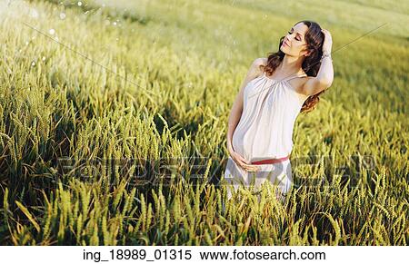 Stock Photography - Adorbale pregnant woman touching her belly. Fotosearch