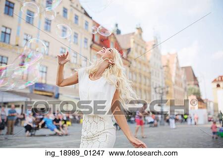 Stock Photo - Alluring blond lady having a grat fun with the soap bubbles. Fotosearch