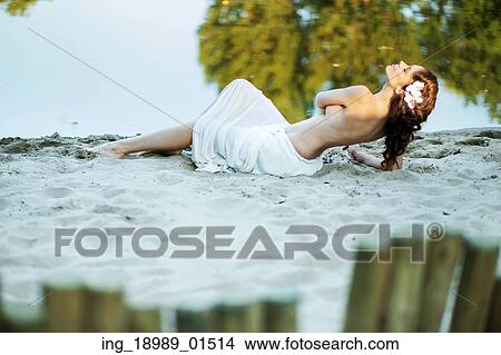 Picture - Alluring lady lying on the white sand. Fotosearch