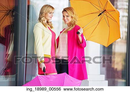 Stock Photograph - Attractive girlfreinds carrying the colorful umbrellas. Fotosearch