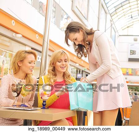 Stock Photo - Attractive lady showing her girlfriends some stuff. Fotosearch