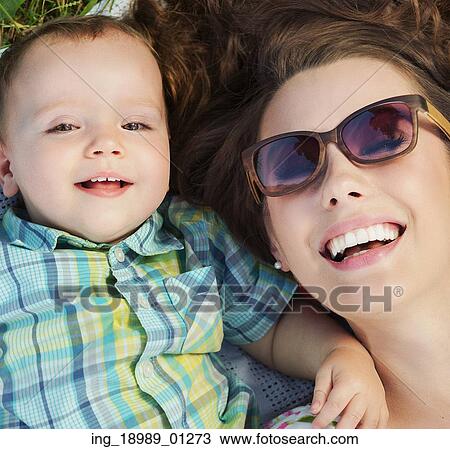 Stock Image - Attractive mom lying on the blanket with her child. Fotosearch