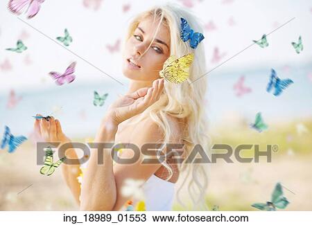 Stock Image - Beautiful woman among hundreds colorful butterflies. Fotosearch