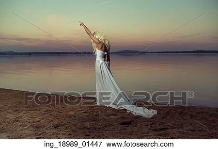 Stock Photo - Blond woman walking on the beach in the evening. Fotosearch