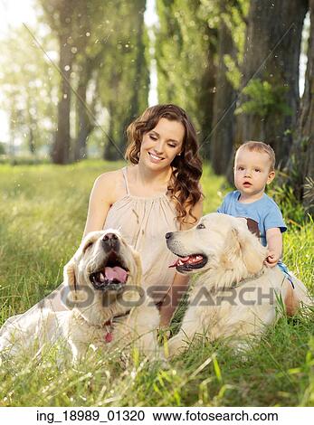 Stock Image - Charming woman with kid and two dogs. Fotosearch