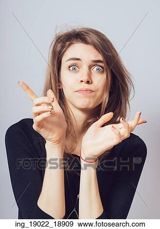 Stock Photo - cheerful beautiful girl shows she does not know what to do. Fotosearch
