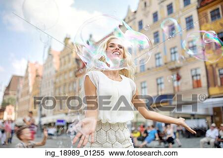 Stock Photography - Cheerful woman looking through the huge bubble. Fotosearch