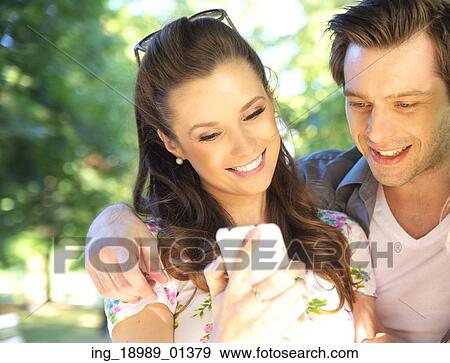Stock Photo - Couple textong to their best friends. Fotosearch