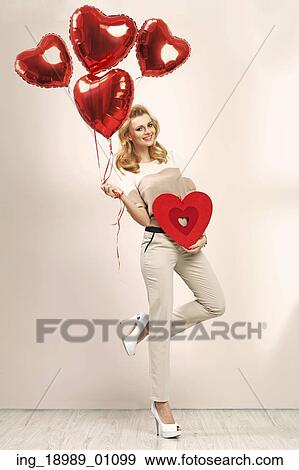 Stock Photo - Cute blonde girl with bunch of veltine&rsquo; s balloons. Fotosearch