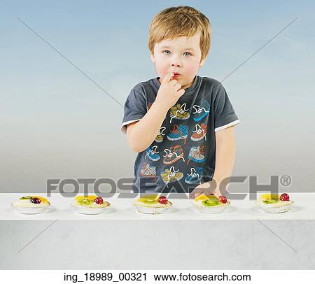 Stock Image - Cute little kid with delicious fruit cake. Fotosearch