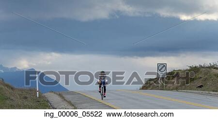 Stock Image - Cyclist riding bicycle on the road, Patagonia, Chile. Fotosearch