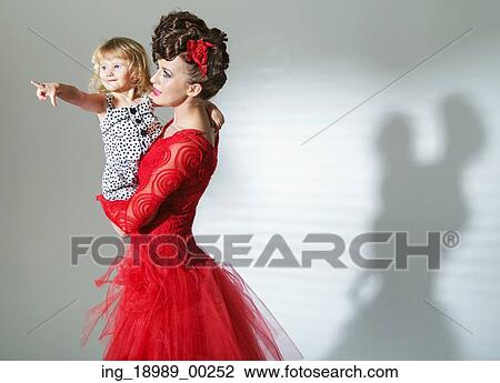 Stock Image - Elegant brunette lady with cheerful daughter. Fotosearch