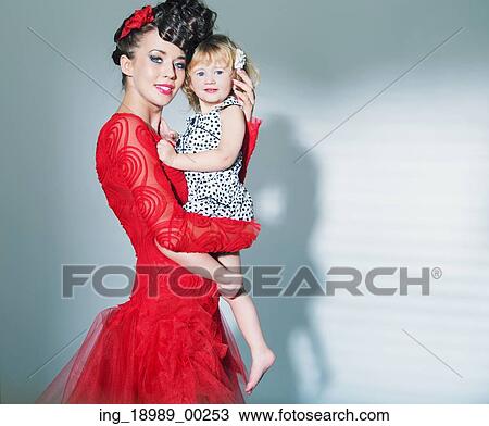 Stock Image - Elegant lady carrying her lovely cute daughter. Fotosearch