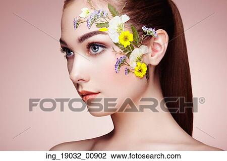 Stock Image - Face of beautiful woman decorated with flowers. Perfect makeup. Beauty fashion. Eyelashes. Cosmetic Eyeshadow. Fotosearch