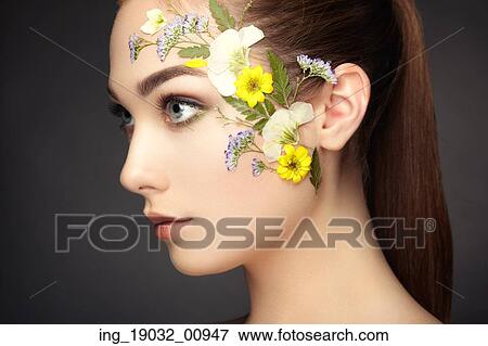 Stock Photo - Face of beautiful woman decorated with flowers. Perfect makeup. Beauty fashion. Eyelashes. Cosmetic Eyeshadow. Fotosearch