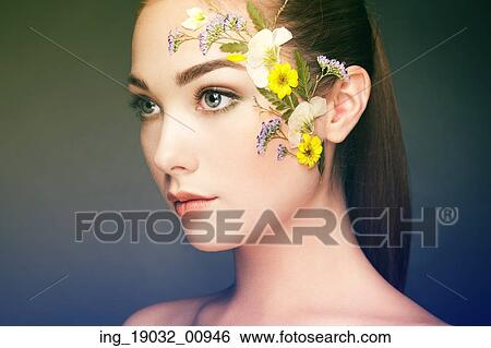 Stock Photograph - Face of beautiful woman decorated with flowers. Perfect makeup. Beauty fashion. Eyelashes. Cosmetic Eyeshadow. Fotosearch