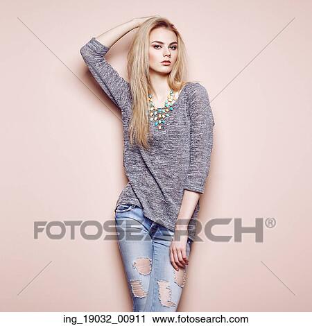 Stock Image - Fashion portrait of beautiful young woman with blond hair. Girl in blouse and jeans. Jewelry and hairstyle. Fotosearch