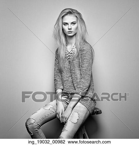 Stock Image - Fashion portrait of beautiful young woman with blond hair. Girl in blouse and jeans. Jewelry and hairstyle. Fotosearch
