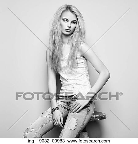 Stock Image - Fashion portrait of beautiful young woman with blond hair. Girl in blouse and jeans. Jewelry and hairstyle. Fotosearch