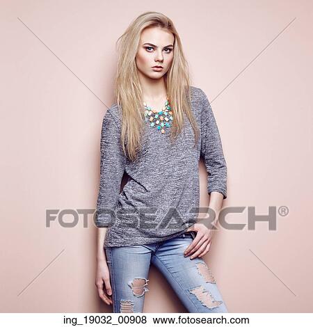 Stock Photo - Fashion portrait of beautiful young woman with blond hair. Girl in blouse and jeans. Jewelry and hairstyle. Fotosearch