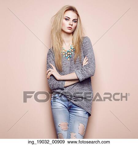 Stock Photo - Fashion portrait of beautiful young woman with blond hair. Girl in blouse and jeans. Jewelry and hairstyle. Fotosearch