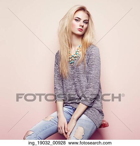Stock Photo - Fashion portrait of beautiful young woman with blond hair. Girl in blouse and jeans. Jewelry and hairstyle. Fotosearch