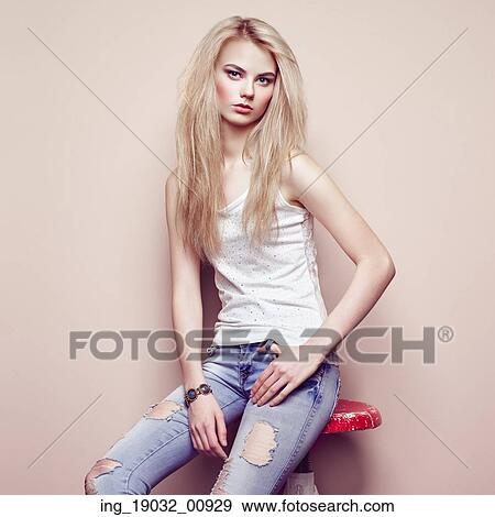 Stock Photo - Fashion portrait of beautiful young woman with blond hair. Girl in blouse and jeans. Jewelry and hairstyle. Fotosearch