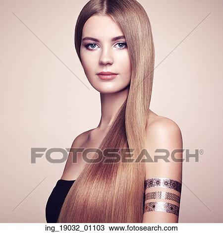 Stock Image - Fashion portrait of elegant woman with magnificent hair. Blonde girl. Perfect make-up. Girl in elegant dress. Flash tattoo gold. Fotosearch