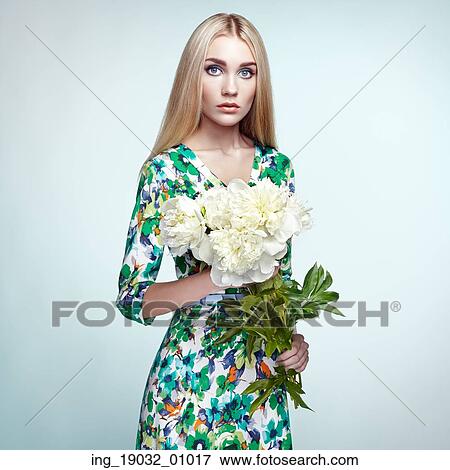 Stock Photo - Fashion portrait of elegant woman with summer flowers. Blonde girl. Perfect make-up. Hairstyle. Summer dress. Peonies. Fotosearch
