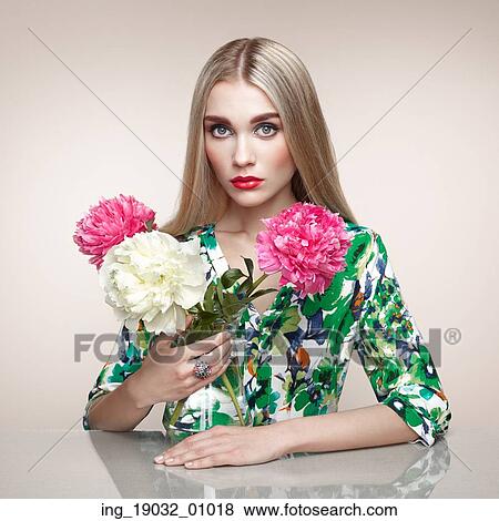 Stock Photo - Fashion portrait of elegant woman with summer flowers. Blonde girl. Perfect make-up. Hairstyle. Summer dress. Peonies. Fotosearch