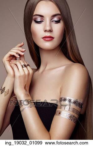 Stock Photo - Fashion portrait of elegant woman with magnificent hair. blonde girl. Perfect make-up. Girl in elegant dress. Flash tattoo gold. Fotosearch