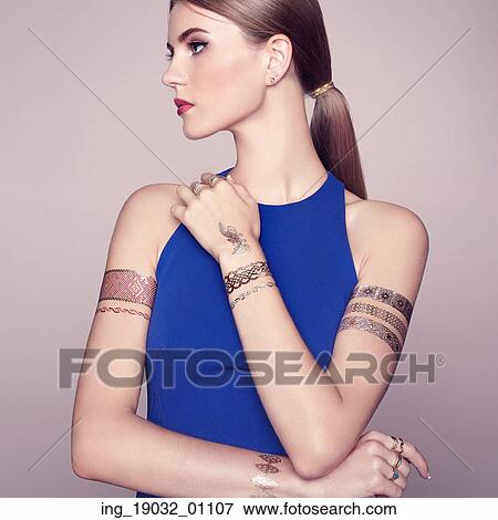 Stock Photo - Fashion portrait of elegant woman with magnificent hair. Blonde girl. Perfect make-up. Girl in elegant dress. Flash tattoo gold. Fotosearch