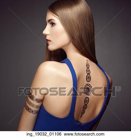 Stock Photograph - Fashion portrait of elegant woman with magnificent hair. Blonde girl. Perfect make-up. Girl in elegant dress. Flash tattoo gold. Fotosearch